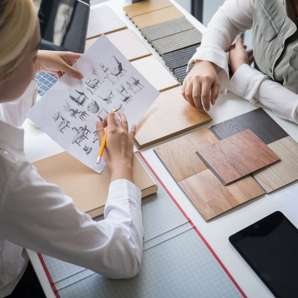 Diseñadores de interiores en La Moraleja seleccionando bocetos de mobiliario y muestras de maderas nobles para proyectos de lujo